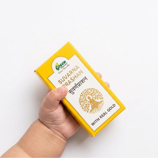Hand holding a yellow box labeled 'Suvarna Rashan' with real gold on a white background