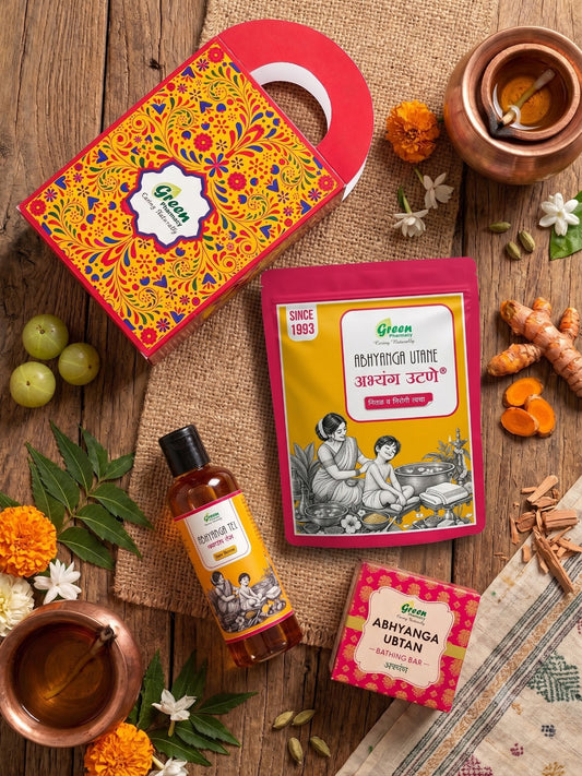 A styled flat-lay of Green brand Ayurvedic wellness products on a rustic wooden surface with burlap, including a decorative gift box, Ashwagandha Utkarsh powder packet, Abhyanga Oil bottle, Abhyanga Urtan box, and a copper cup with oil.